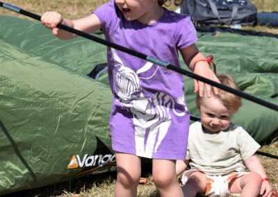 A young child helping put a tent up by holding a tent pole