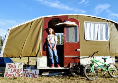 Photo of a young person standing in the doorway of a vintage style caravan