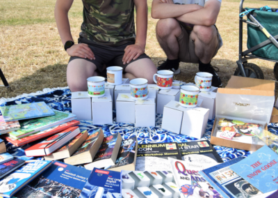 Close up photo of two young people with a display of items on sale laid out on the floor in front of them