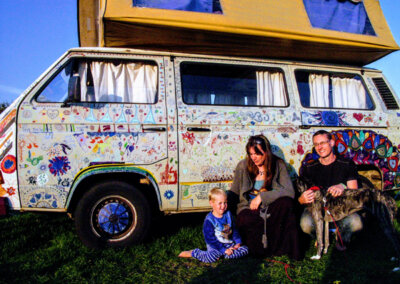 Photo of a family sitting in front of their brightly decorated camper van