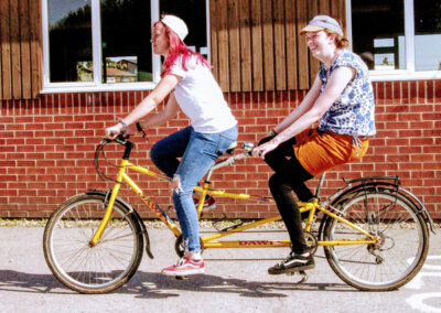 Photo of two adults riding a tandem bycycle