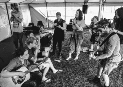 Black and white photo of a group of people jamming in a marquee