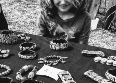 Black and white photo of a young child selling jewellery from a table