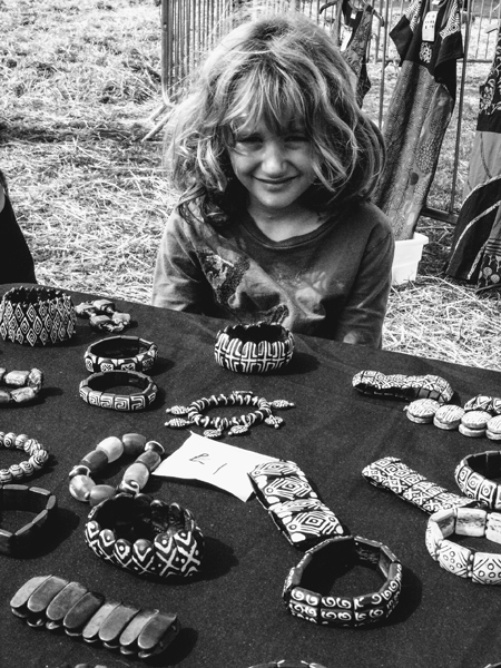 Black and white photo of a young child selling jewellery from a table