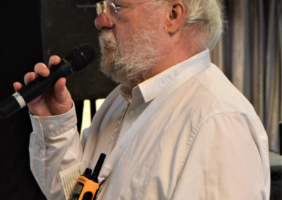 Photo of a man in a white shirt speaking into a microphone