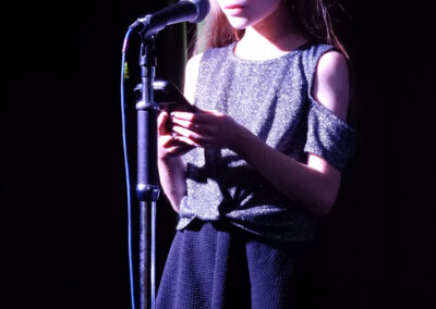Photo of a young person standing in front of a microphone on stage