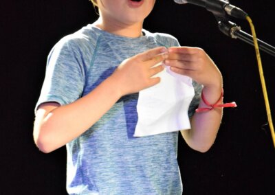 Photo of a young person standing on stage in front of a microphone