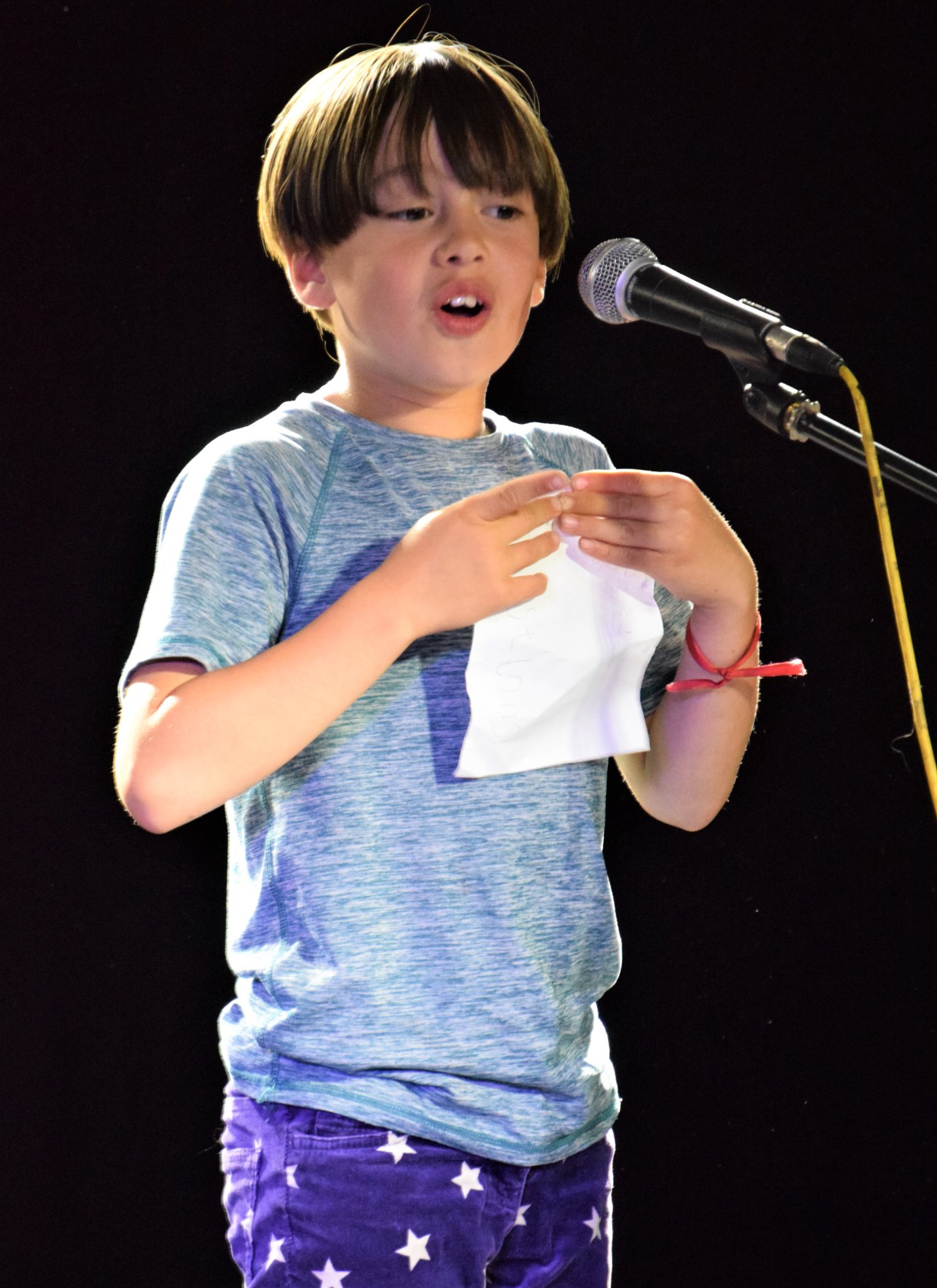 Photo of a young person standing on stage in front of a microphone