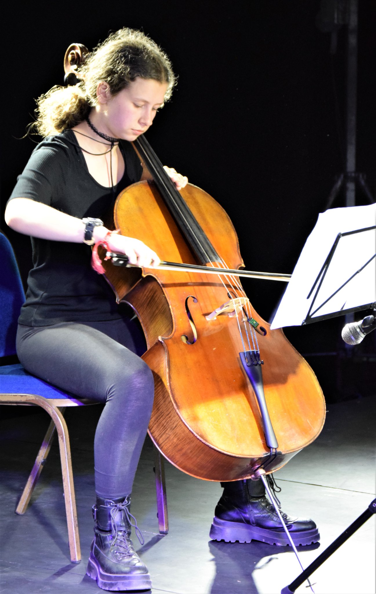 Photo of a young person playing an cello on stage