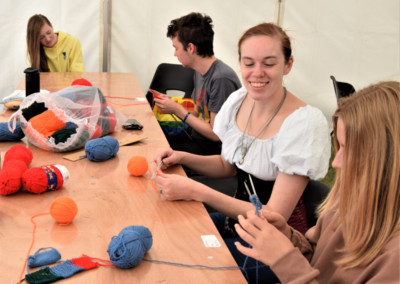 Photo of four people sat at a table and working with yarn