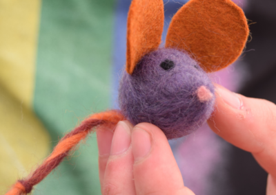 Close up photo of a needle felted mouse being held in a hand