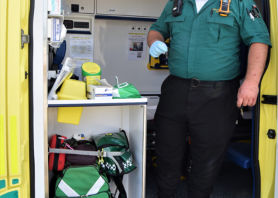 Photo of a man dressed in ambulance crew uniform standing in the doorway of a community ambulance.