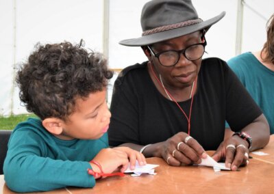 Photo of a woman showing a young person how to do origami