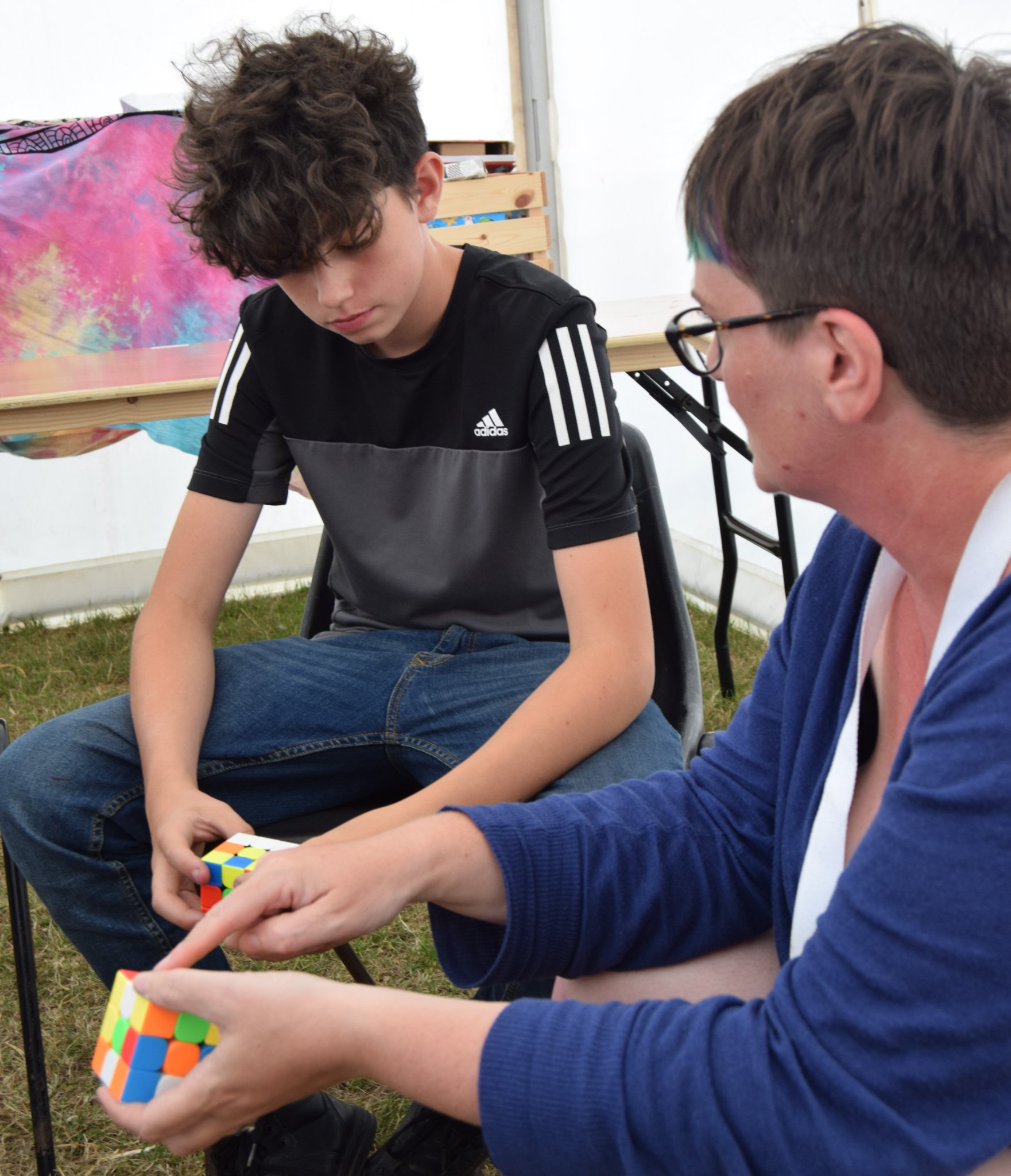 Photo of a woman demonstrating to a young person how to do a Rubik's Cube