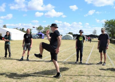 Photo of five people standing in a field with a sixth person demonstrating running skills