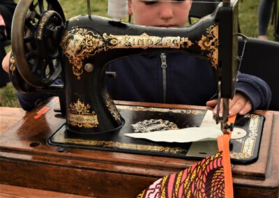 Photo of a young child using a vintage Singer hand crack sewing machine