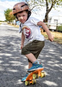 Photo of a young boy wearing a helmet and riding a skateboard
