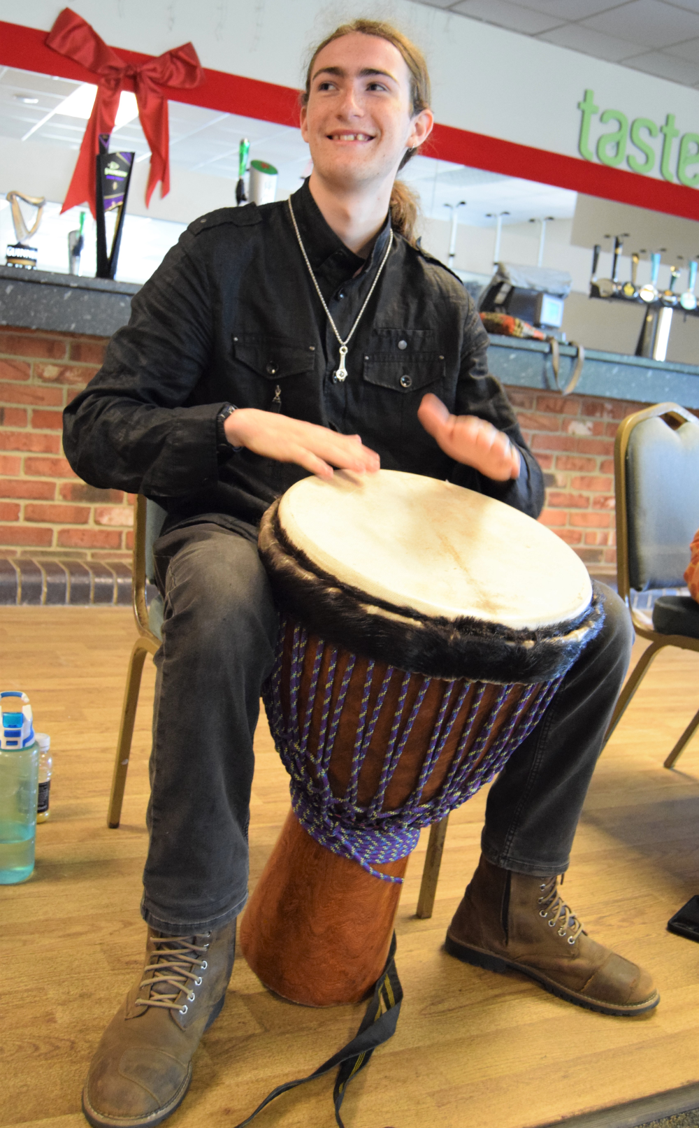 Photo of a man sat playing a West African drum