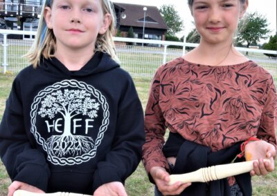 Photo of two young people holding pieces of wood that have been shaped on a woodturner