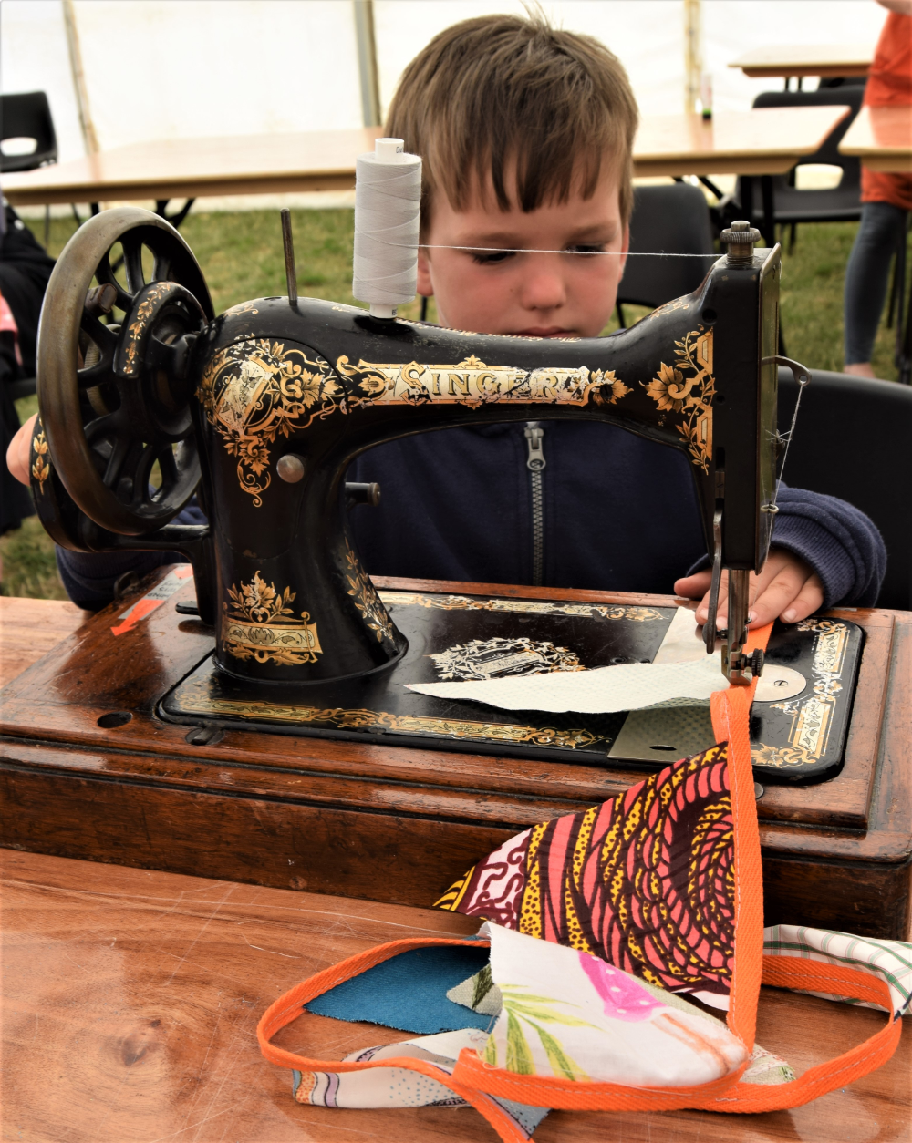 Young person sat in front of a handcrank sewing machine